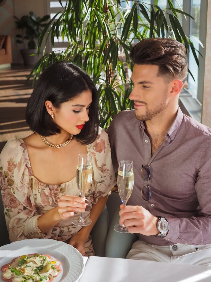 A stylish couple enjoying champagne at a sophisticated indoor setting. Perfect moment of romance and elegance.